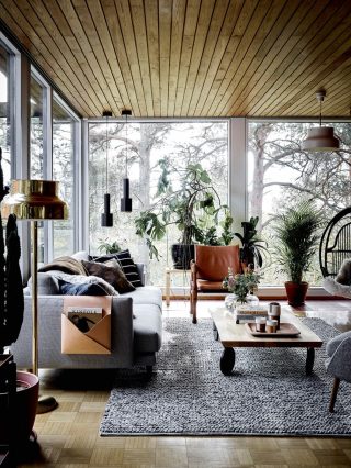 LIVING The Lazy sofa, matching Day chair, Woody coffee table and Note organiser (on the arm of the sofa) in this space are all by Hakola, while the leather safari chair is 
a vintage find. Annaleena is a collector of 1968 Bumling lamps by Anders Pehrson – two are seen here, in gold (foreground) and grey (top right). The black pendant lights (back left) are by Artek.LIVING The glass-walled living 
area provides an unparalleled connection to nature and makes relaxation effortless; daydreaming in the hanging chair by Parolan Rottinki has become a heavenly pastime. Surrounded by tall pine, birch and juniper trees, the 
family’s privacy is assured, yet 
the huge windows let in loads 
of light, which allows their indoor jungle to thrive.