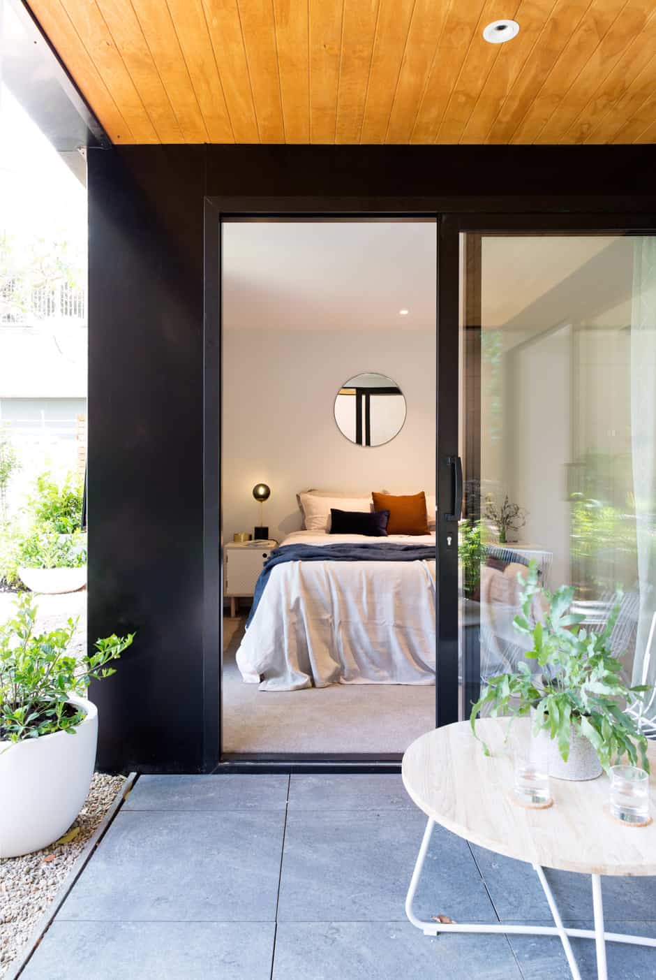 FAR LEFT In the guest bedroom, Botanical Garden by Billie Culy is reflected in a Circular mirror by Mark Antonia. On the bedside table by Homebase Collections is a Line table lamp by Douglas and Bec. LEFT The bathroom vanities echo the kitchen cabinetry. BELOW Glinks Gully by Duncan Innes features in the master bedroom, where a Monmouth Glass Studio pendant is suspended over a Douglas and Bec bedside table. OPPOSITE The guest room connects to the courtyard and would work equally well as a second living area or study. 