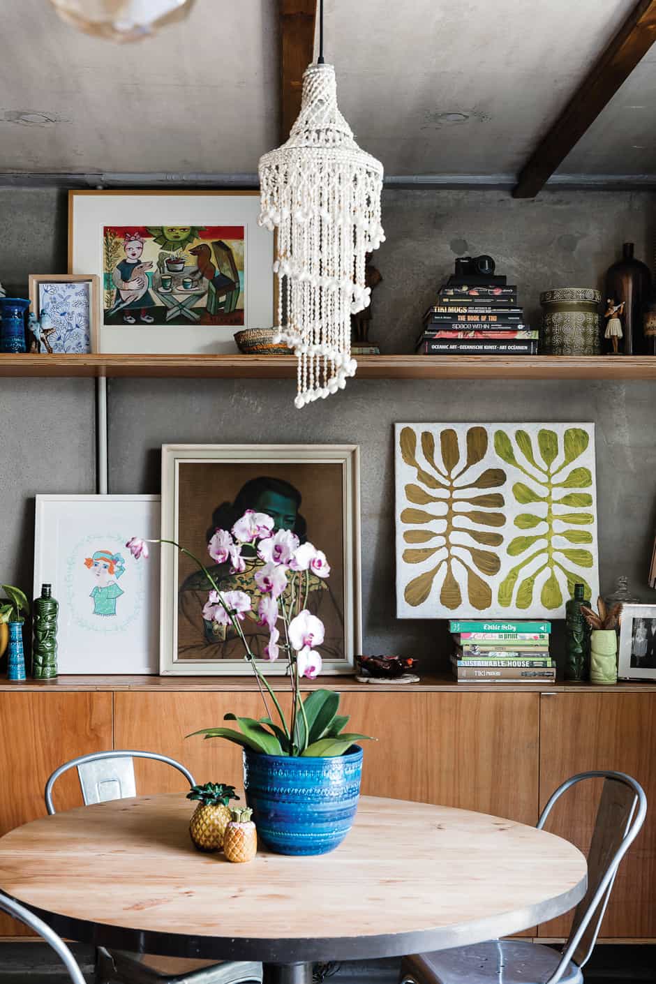 SHELVE IT In the dining area, where the family gathers at the $20 op shop table the couple sanded and painted, Susanna’s framed illustrations rub shoulders with an eye-catching collection of vintage paintings and souvenirs, as well as pottery finds from Australia and Paul’s native New Zealand. Susanna has repurposed her favourite blue Bitossi vase as a planter for an exotic orchid.