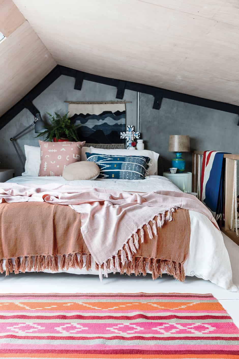 MASTER BEDROOM The couple’s attic bedroom is filled to the brim with an eclectic collection of items, including a rug from Argentina, throws by Citta Design and a Componibili storage unit by Anna Castelli Ferrieri for Kartell paired with a thrift store lamp. 